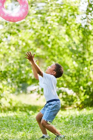 African boy throws and catches a swimming ring during the holidaysの写真素材