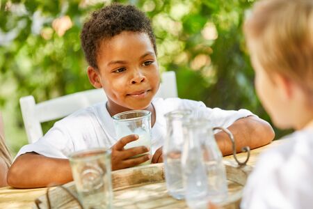 African boy is drinking milk for breakfast in international kindergartenの写真素材