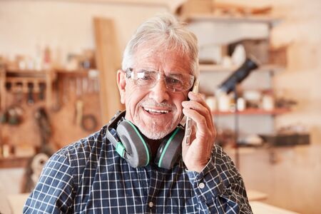 Senior craftsman with mobile phone at customer service takes an order