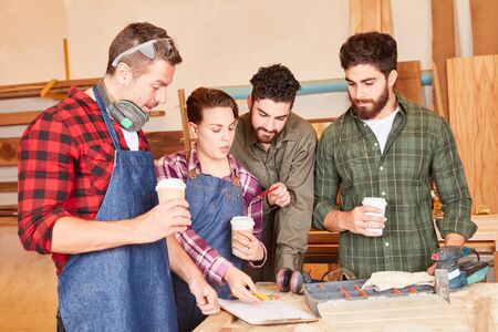 Young craftsman team with apprentices in a meeting in the carpenter workshop