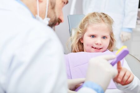 Child gets dental care tips from pediatric dentist for dental health and as prophylaxisの写真素材
