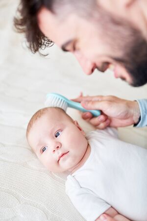 Caring father removes the milk scab from his baby with a brushの写真素材