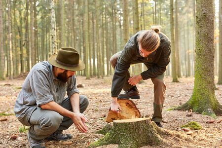 Man training to the forester in the woods while marking a felled tree