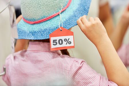 Girl at the hat buying in the fitting in a boutique during 50% saleの写真素材