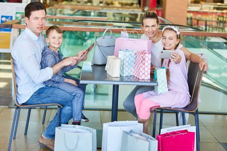 Family and children with many shopping bags and smartphone in shopping arcadeの写真素材
