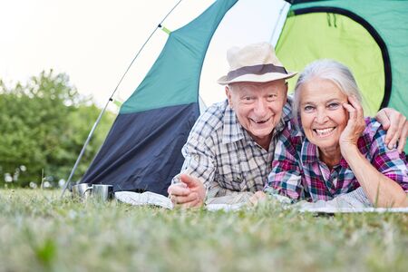 Happy senior couple relaxes while camping in tent while camping in natureの写真素材