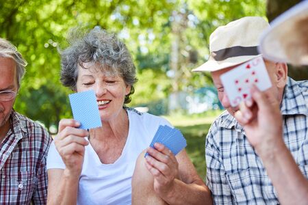 Seniors play cards together in the park for relaxation or competition