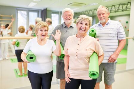 Happy seniors with yoga mats in the gym are looking forward to the back exercisesの写真素材