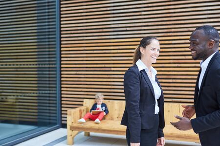 Two laughing business people talking in a break in front of the office building
