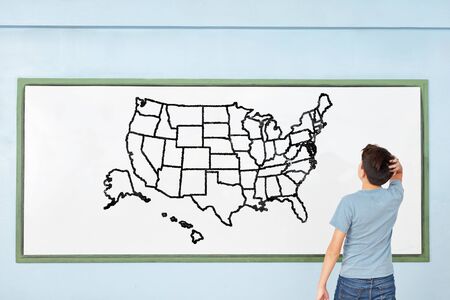 Child in elementary school is in front of map of the USA on whiteboardの写真素材