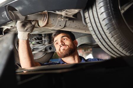 Automotive mechatronics engineer checks an exhaust for the exhaust emission inspection in the workshopの写真素材