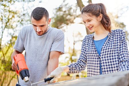Young couple at the garden furniture work up or renovate together as a home improvement workの写真素材