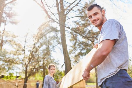 Young couple together carrying a tabletop while moving to their new home in the summerの写真素材