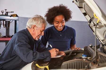 Car Master and African woman as a mechatronics apprentice at the auto inspectionの写真素材