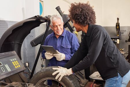 Woman as a mechatronics apprentice tire assembler with instructor and tablet computerの写真素材