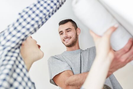 Couple in wallpapering along with wallpaper on wall while renovating an apartmentの写真素材