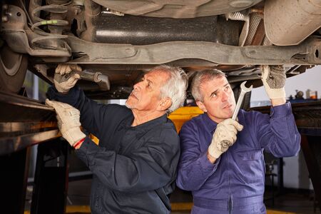 Mechanic or mechatronics repair car or inspect underbody protectionの写真素材