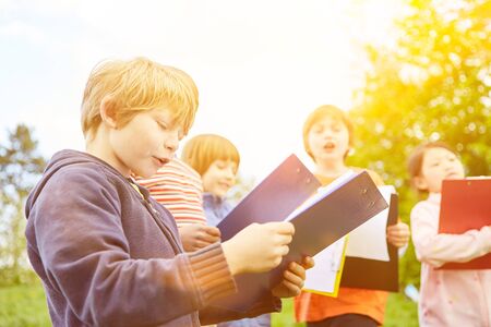 Children with clipboard play scavenger hunt at children's birthday in summerの写真素材