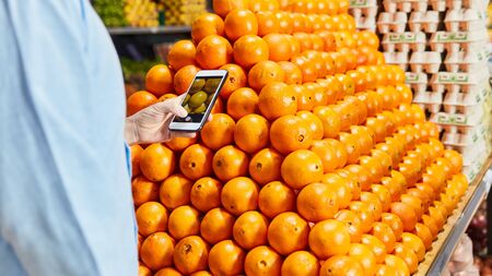 Customer uses smartphone app when buying fresh fruit in the supermarketの写真素材