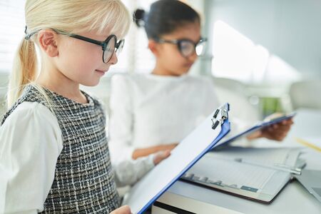 Girl as a business woman with a checklist on the clipboard in the office