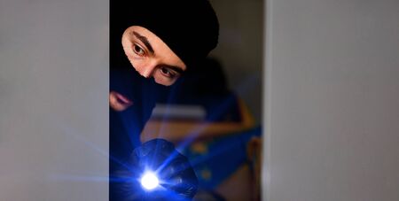 Burglar breaking into a house with flashlightの写真素材