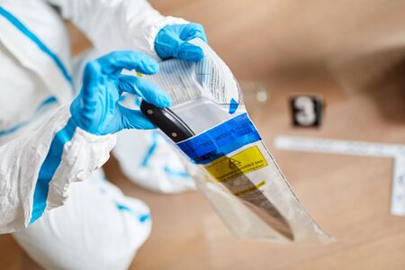 Forensic police at the scene of a crime packs knives in a bag of evidence