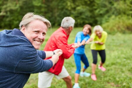 Senior team at tug of war as teambuilding exercise at a workshopの写真素材