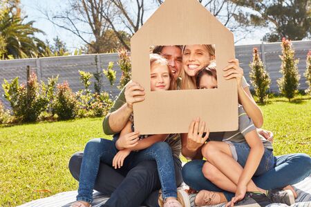 Family with two children is holding umbrella over head as a symbol of home construction and insuranceの写真素材