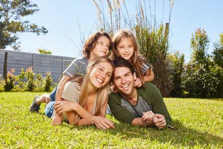 Two children lie together with their parents on a meadow in the summer vacation