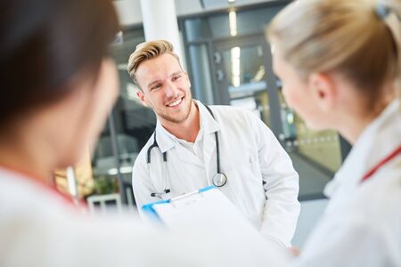 Young medical student or medical assistant talking to team colleagues at university clinic