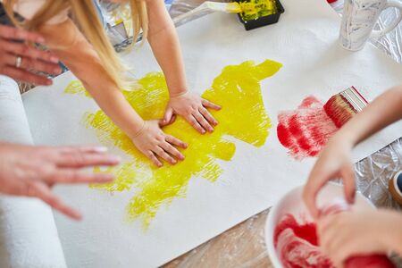 Children paint a wallpaper with their hands as a creative game while renovatingの写真素材