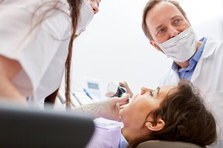 Dentist team and patient at the professional cosmetic whitening in the dental officeの写真素材