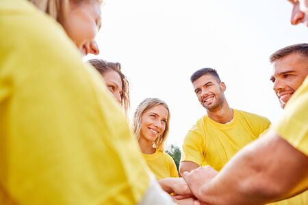Young people as start-up team in a team building event stack hands