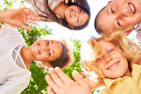 Cheerful children in a multicultural kindergarten wave at the camera