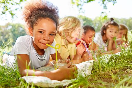 African girl and friends drink water with strawの写真素材