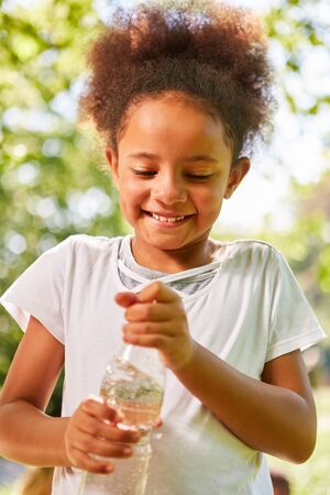 Merry African girl with a bottle of mineral waterの写真素材