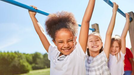 Multicultural kids shimmy on jungle gym on the trim path