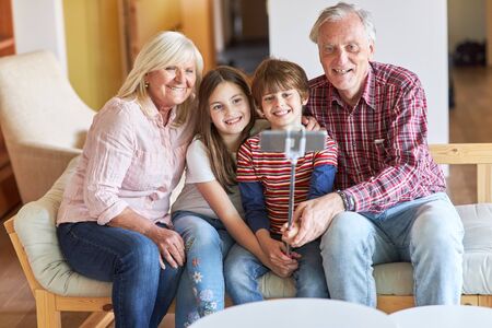 Grandparents and kids take a selfie photo with smartphone on selfie stick