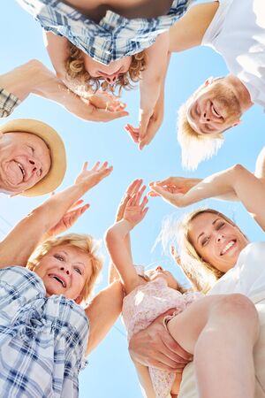 Cheering three generations family with grandparents and children in the sunの写真素材