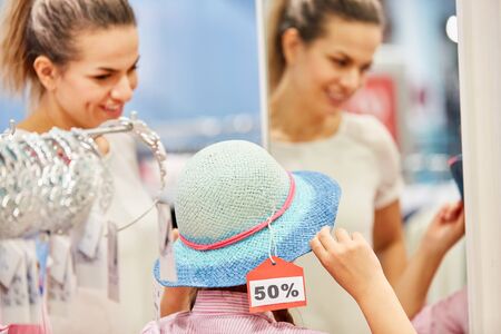 Girl at the hat shop during 50% sale with mother in a boutiqueの写真素材