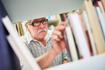 Senior man researching for education in the library in the senior residenceの写真素材
