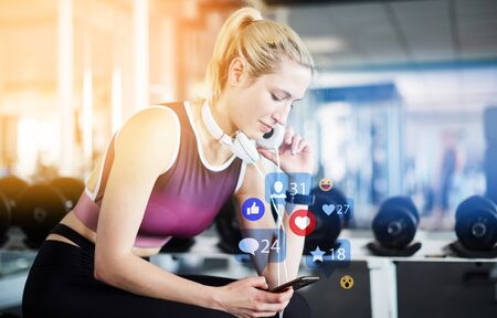 Young woman gives rating on smartphone while exercising in fitness center