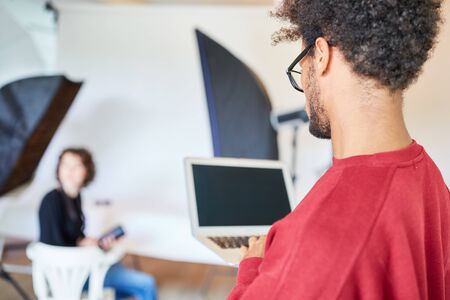 Young photographer at the laptop computer is preparing a photo shoot