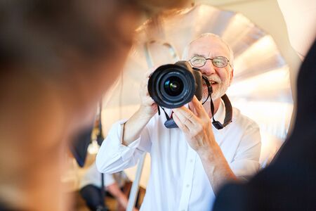 Senior photographer with digital camera takes pictures of a womanの写真素材
