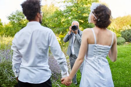 Wedding photographer takes pictures of newlyweds in nature on wedding dayの写真素材