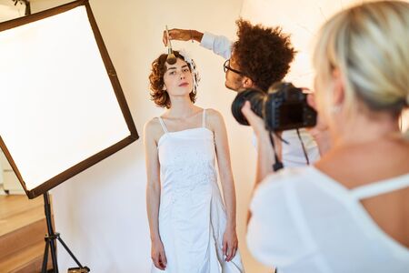 Make-up artist or makeup artist applying make-up to a bride in a photo studioの写真素材