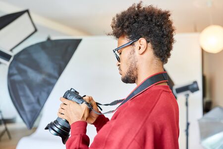 Young photographer or photo student is examining settings on his cameraの写真素材