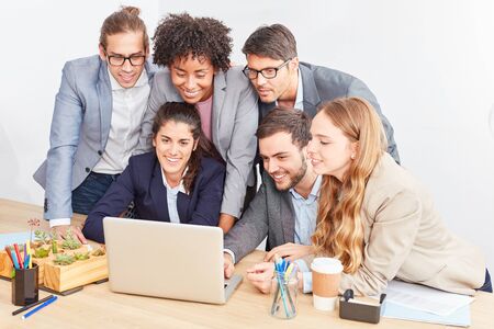 Creative young internet start-up team looks together on laptop computer