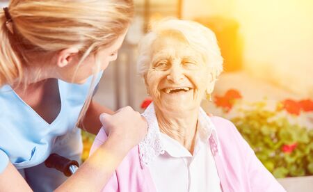 Laughing elderly woman with a caring nurse in a retirement home