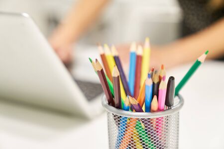Crayons next to the laptop on the desk as a symbol of creativity and designの写真素材
